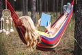 Woman resting in hammock and reading book to improve her mindfulness and mental health Royalty Free Stock Photo