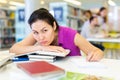 Woman resting her head on stack of books in public library