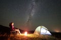 Woman resting at night camping in mountains under starry sky