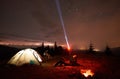 Woman resting at night camping near campfire, tourist tent, bicycle under evening sky full of stars Royalty Free Stock Photo