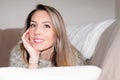 Woman resting on sofa hand on chin lying on brown couch home