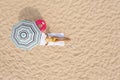 Woman resting under striped beach umbrella at sandy coast, aerial view. Space for text Royalty Free Stock Photo