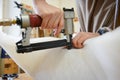 Woman restoring chair in upholstery workshop with pneumatic stapler. Royalty Free Stock Photo