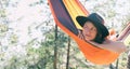 Woman rests alone in tourist hammock in sunny pine forest enjoying her loneliness, sense of peace and serenity. Natural moments