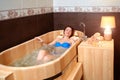 A woman rests in a wooden bath made of cedar