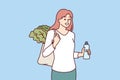 Woman with reusable eco shopping bag and recycled plastic bottle returns from farmer market