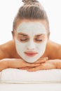 Woman with revitalising mask on face laying on massage table