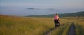 The woman is ride on bike against the backdrop of hills in dense fog at sunset in the picturesque valley. The girl Royalty Free Stock Photo