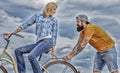 Woman rides bicycle sky background. Service and assistance. Man helps keep balance ride bike. Girl cycling while man Royalty Free Stock Photo