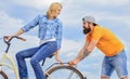 Woman rides bicycle sky background. Service and assistance. Man helps keep balance ride bike. Girl cycling while man Royalty Free Stock Photo