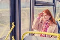 A woman rides a bus and looks at the route of traffic outside the window. The girl looks at the road putting her hand to her