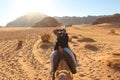 Woman rides a camel and tries to take photos in desert Royalty Free Stock Photo