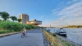 Woman bikes along the Rhine River promenade in Cologne with the famous Bastei 1920\'s Restaurant in the bakground. Royalty Free Stock Photo