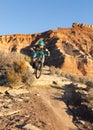 A woman rides a mountain bike down a trail below Gooseberry mesa in the Southern Utah desert Royalty Free Stock Photo