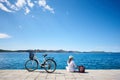 Woman riding a bicycle along stony sidewalk on blue sparkling sea water Royalty Free Stock Photo