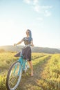 Woman riding bicycle cruiser on countryside path in summer.