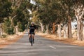 Woman riding bicycle on empty road. Cyclist rides her bike through empty countryside highway Royalty Free Stock Photo