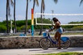 Woman riding a bicycle and reading a text message on her phone Miami Beach Spring Break scene