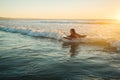 Woman riding a bodyboard at sunset