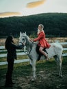 Woman riding grey arabian horse in pink dress. Handsome bearded man driving horse for a bridle and looking at his Royalty Free Stock Photo