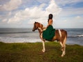 Woman riding horse near the ocean. Outdoor activities. Asia woman wearing long green dress. Traveling concept. Cloudy sky. View Royalty Free Stock Photo