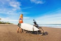 Woman riding a motorcycle with the surfboard