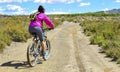 Woman riding a mountain bike by a muddy path of dirt