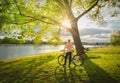 Woman riding a mountain bike near lake at sunset in summer Royalty Free Stock Photo