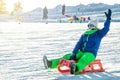 Woman riding on a red sled descends down the mountain