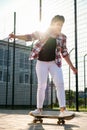 Woman riding a skateboard on street. Skater girl on a longboard. Cool female skateboarder at sunset. Carefree female Royalty Free Stock Photo