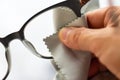 Woman right hand cleaning shortsighted or nearsighted eyeglasses by grey microfibre cleaning cloths, On white background