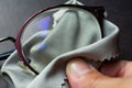 Woman right hand cleaning shortsighted or nearsighted eyeglasses by microfibre cleaning cloths, On black background, Close up Royalty Free Stock Photo