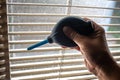 Woman right hand squeezing blue blower for cleaning dust blinds inside a window, Blurred dust and Dirty mosquito wire screen Royalty Free Stock Photo