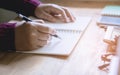 Woman right hand writing on notebook at home area in morning with sun light