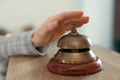 Woman ringing hotel service bell at wooden reception desk, closeup Royalty Free Stock Photo