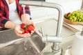 Woman rinses the strawberries in the kitchen