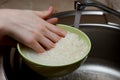 Woman rinsing rice in bowl under running water Royalty Free Stock Photo