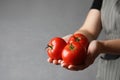 Woman with ripe tomatoes on grey background, closeup. Space for text