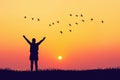 Woman rising hands and birds flying on sunset sky at nature field abstract background. Freedom feel good and travel adventure