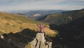 Woman rising up hands aerial. Tourist girl sit on mountain rock top. Nature landscape at autumn day