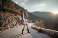 Woman road mountain. A woman in a white sweater, black boots and a hat walks along a winding alpine path between the Royalty Free Stock Photo