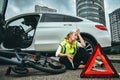 Woman in road vest repairing car and a bicycle Royalty Free Stock Photo