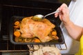 Woman roasting chicken in oven