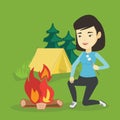 Woman roasting marshmallow over campfire.