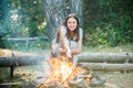 Woman roasting marshmallows near bonfire. Young woman having a camping.