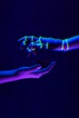 Woman and robot`s hands as a symbol of connections between people and technology. Neon colors.