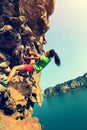 Woman rock climber climbing at seaside mountain rock wall Royalty Free Stock Photo