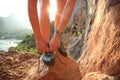 Woman rock climber tying shoelace on rock