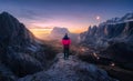 Woman on the rock and mountain peaks at night in autumn