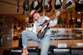 Woman rocker playing guitar connected to amplifier over shop store background